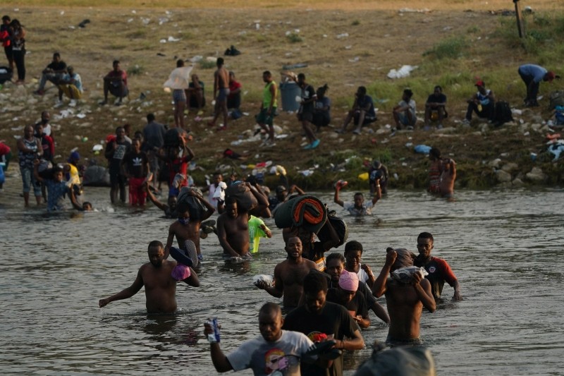 Ciudad Acuna : Migrants, many from Haiti, wade across the Rio Grande from Del Rio, Texas, to return to Ciudad Acuna, Mexico, Tuesday, Sept. 21, 2021, to avoid deportation from the U.S.  The U.S. is flying Haitians camped in a Texas border town back to their homeland and blocking others from crossing the border from Mexico. (AP/PTI Photo)
